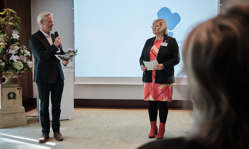 Dr. Andreas Beilken und Sabine Brase kündigen die Präsentation des Preisträgerteams 2024 an.
